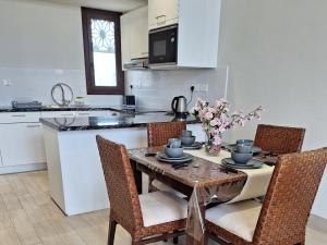 eine Küche mit einem Tisch mit Stühlen und Blumen darauf in der Unterkunft Hawana Salalah Lake View Villa 22 in Salalah