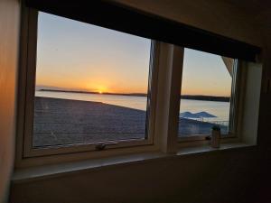une fenêtre avec vue sur l'océan et le coucher du soleil dans l'établissement Restaurang Sjövik, à Motala