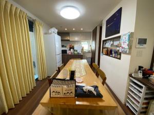 a kitchen with a long wooden table and a room at Fukuoka Guest House Jikka in Fukuoka
