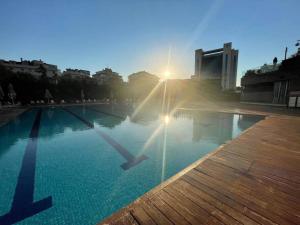 a swimming pool with the sun setting in the background at Newada Residence 1+1 With Pool View in Istanbul