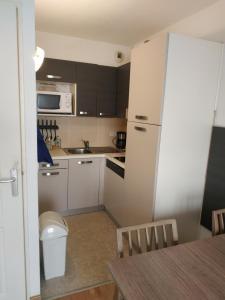 a kitchen with a white refrigerator and a table at Studio au cœur de Valberg à proximité des pistes in Valberg
