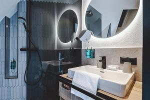 uma casa de banho com um lavatório branco e 2 espelhos em The Gast House Zell am See em Zell am See