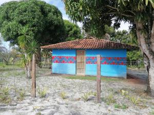 un bâtiment bleu et rouge avec un arbre dans l'établissement Maison de plage à Santo Antonio, à Santa Cruz Cabrália