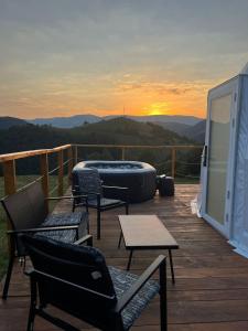 a deck with chairs and tables with a sunset in the background at Tranquil Dome - Manta's Retreat Glamping Cornereva in Cornereva