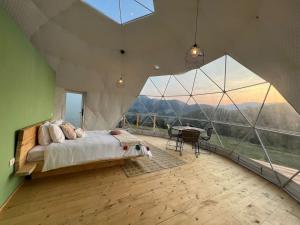 a bedroom with a bed and a large glass window at Tranquil Dome - Manta's Retreat Glamping Cornereva in Cornereva