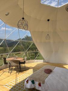 a bedroom with a bed and a table and chairs at Tranquil Dome - Manta's Retreat Glamping Cornereva in Cornereva