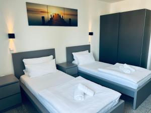 2 Einzelbetten in einem Zimmer mit einem Bild an der Wand in der Unterkunft Lipp Apartments in Köln