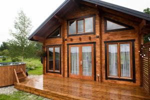 ein Holzhaus mit einer Terrasse und einem Whirlpool in der Unterkunft Saunamajutus Öötlas 