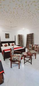 um quarto com uma cama, uma mesa e cadeiras em Colonels Homestay em Udaipur