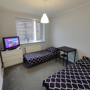 a bedroom with two beds and a desk with a television at Makuszyńskiego in Gdynia