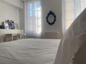 a white bed in a white room with a mirror at Maison d’hôtes Le 1853 in Narbonne