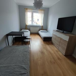 a living room with a flat screen tv and two beds at Makuszyńskiego in Gdynia