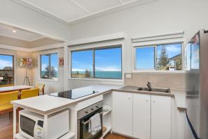 a kitchen with white cabinets and windows and a table at Blue Waters in Point Lookout