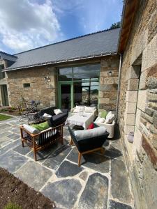un patio con divani e sedie su un muro di pietra di Le Clos Luly a Neulliac