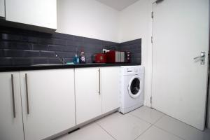 eine weiße Küche mit Waschmaschine in der Unterkunft Spacious 5 Bedroom Apartment In Swansea in Swansea + 27 Fotos