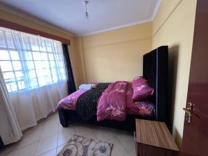 Un dormitorio con una cama con sábanas moradas y una ventana en Naivasha 1BR Apartment, en Naivasha