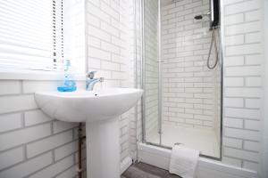 een witte badkamer met een wastafel en een douche bij Spacious 5 Bedroom Apartment In Swansea in Swansea