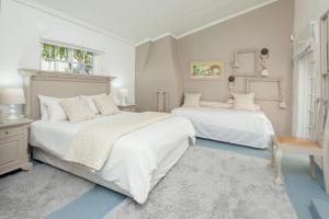 een witte slaapkamer met 2 bedden en een raam bij The Lady Grace in Greyton