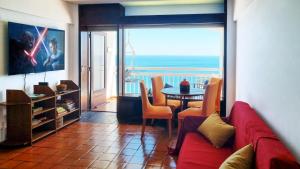 a living room with a red couch and a table with chairs at Sesimbra Sun&Sea - Beachfront Apartment! in Sesimbra