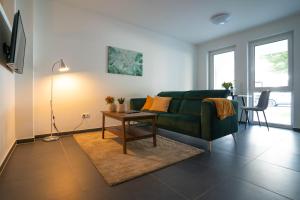 a living room with a green couch and a table at Modernes Ferienapartment: Komfort & Wohlfühlen in Fuldatal