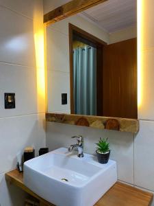 uma casa de banho com um lavatório branco e um espelho. em Hospedaria Cambará em Cambará