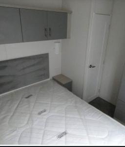 een wit bed in een kleine kamer met een deur bij Langford Lodge in Great Billing