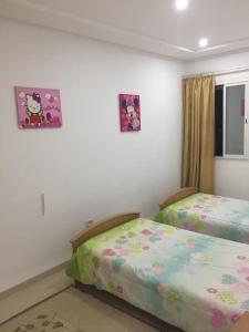 a bedroom with two beds and two pictures on the wall at maison d'hôte familiale للعائلات فقط in Sousse