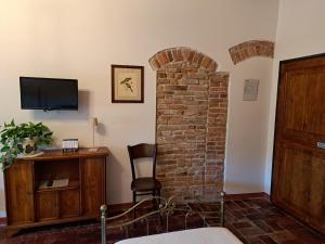 Habitación con un pilar de ladrillo, una silla y TV en Corte Ramedello, en Cerea