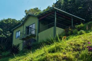 una casa verde al lado de una colina en The Green Shack, en Quatre Soeurs