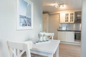 eine weiße Küche mit einem weißen Tisch und Stühlen in der Unterkunft Landhaus am Meer - Whg 3 Liinsand in Utersum