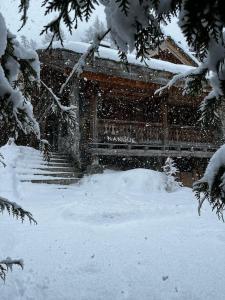 a snow covered house with stairs in the snow at Chalet NANOUK in Le Joseray