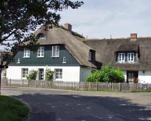 a large white house with a thatched roof at Landhaus am Meer - Whg 2 Süderaue in Utersum