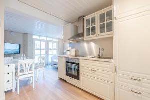 a kitchen with white cabinets and a dining room at Landhaus am Meer - Whg 2 Süderaue in Utersum