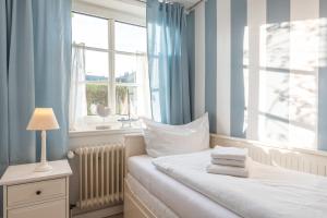 a bedroom with a bed with blue curtains and a window at Landhaus am Meer - Whg 2 Süderaue in Utersum