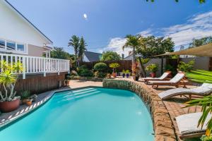 a swimming pool in a yard with chairs and a house at African Breeze Guesthouse in Knysna