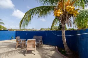 einen Tisch mit Stühlen und eine Palme neben einem blauen Zaun in der Unterkunft Tahir & Tamir Apartment in Willemstad