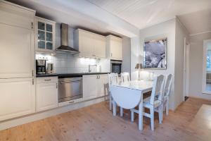 a kitchen with white cabinets and a table and chairs at Landhaus am Meer - Whg 4 Rungholtsand in Utersum