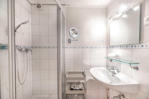 a white bathroom with a sink and a shower at Landhaus am Meer - Whg 4 Rungholtsand in Utersum