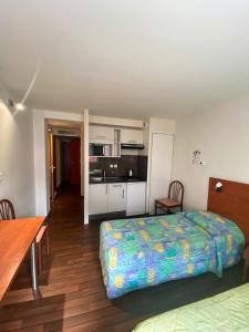 a small bedroom with a bed and a kitchen at Résidence du Soleil in Lourdes