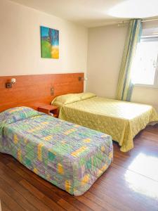 a hotel room with two beds and a window at Résidence du Soleil in Lourdes