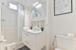 La salle de bains blanche est pourvue d'un lavabo et d'une douche. dans l'établissement Studio cosy proche Paris - 2 min RER Gentilly, à Gentilly