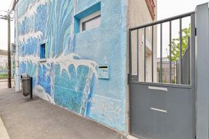 un mur bleu avec graffiti sur un bâtiment avec porte dans l'établissement Studio cosy proche Paris - 2 min RER Gentilly, à Gentilly