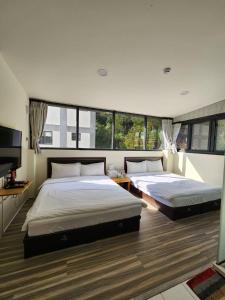 a bedroom with two beds and a flat screen tv at 念念Nian Nian Taomi Inn in Puli