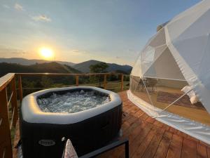 a hot tub on a deck with the sunset in the background at Starry Dome - Manta's Retreat Glamping Cornereva in Cornereva