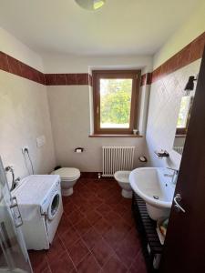 baño con 2 aseos, lavamanos y ventana en Lo Chalet del Golf Club en Tarvisio