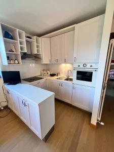a white kitchen with white cabinets and a sink at Lo Chalet del Golf Club in Tarvisio
