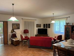a living room with a red couch and a tv at Villa Franca in Castelluccio Inferiore