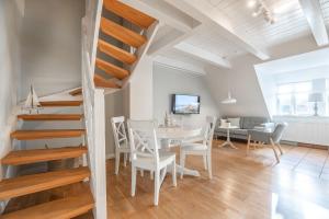 a dining room and living room with a staircase and a table and chairs at Landhaus am Meer - Whg 8 Westerley in Utersum