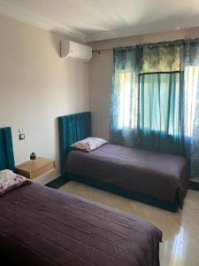 - 2 lits dans une chambre dotée de rideaux bleus dans l'établissement appartement en plein centre de casablanca, à Casablanca