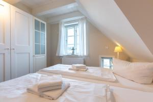 a white bedroom with a bed with two towels on it at Landhaus am Meer - Whg 8 Westerley in Utersum